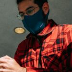 man in red and black plaid button up shirt wearing blue mask
